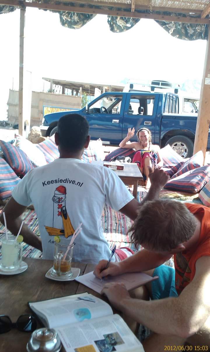 People relaxing in a Bedouin beach cafe in Dahab with cushions and drinks, a Keesiedive.nl shirt visible, June 2012