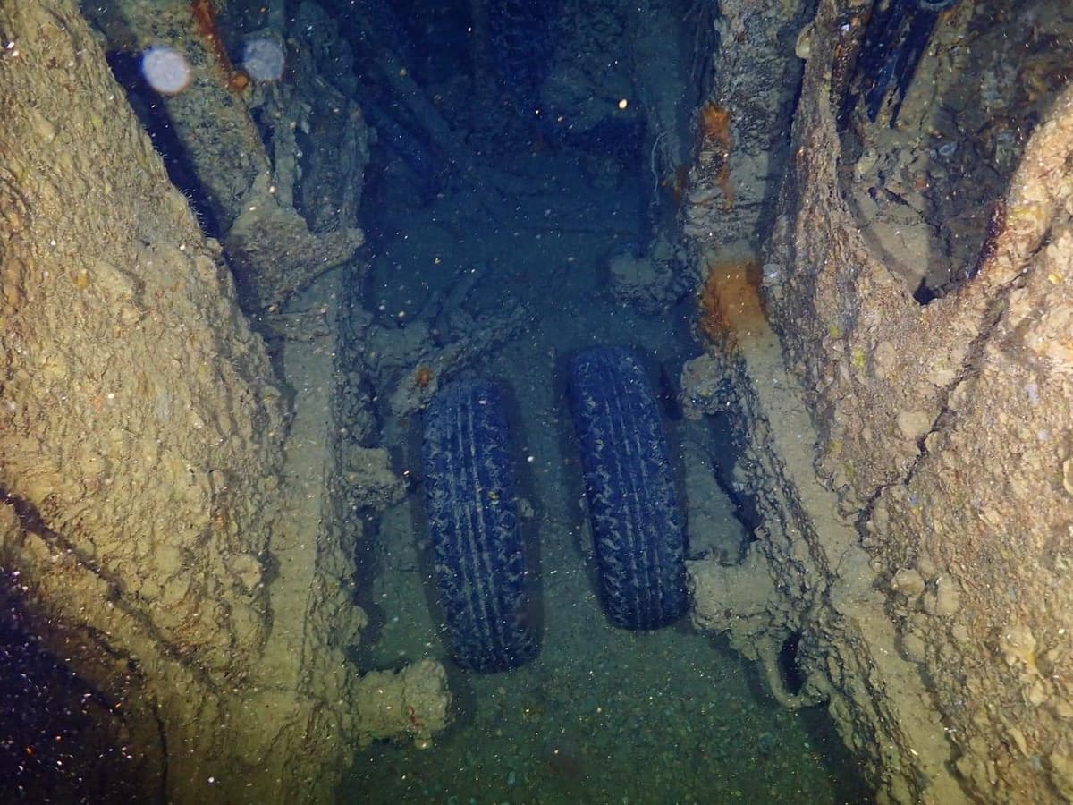 Two military truck tires resting on the floor of the SS Thistlegorm cargo hold, surrounded by corroded metal walls