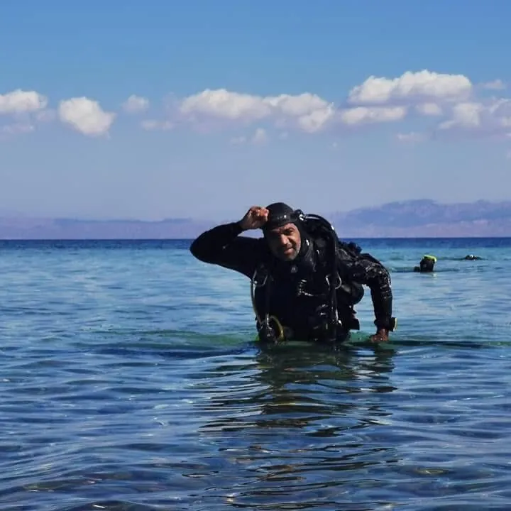 Osama standing chest deep in the sea at Dahab with the Sinai mountains behind him