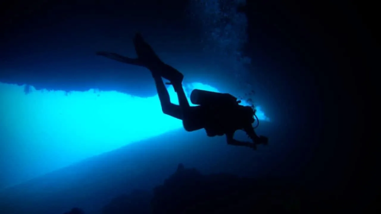 A diver silhouetted in open blue water at twelve metres, photographed by Osama